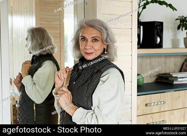 Portrait of confident senior woman in front of mirror at home