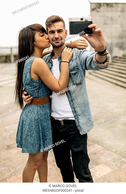 Spain, Gijon, young couple taking a selfie with an old camera