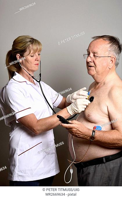 England Uk Member of a Hospial Cardiac Measurement Team Installing A Ambulatory Ecg Monitor To An Overweight Male Patient