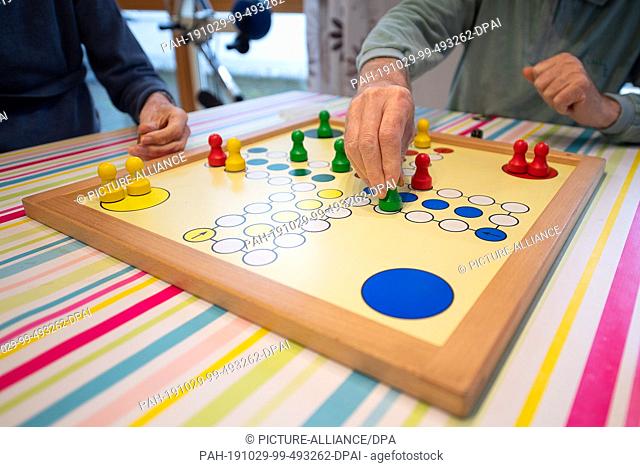 29 October 2019, Baden-Wuerttemberg, Frickenhausen: Two men play the game ""Mensch ärgere Dich nicht"" in a group of senior citizens for people with...