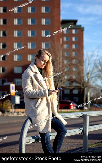 Young woman using smart phone in street