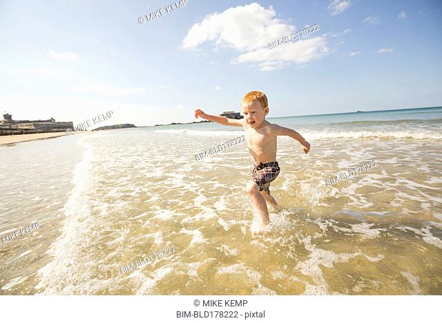 Caucasian boy playing in waves on beach