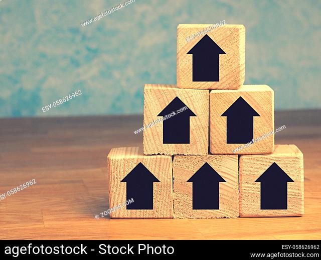 Pyramid of wooden blocks with upswing arrows, growth or aim high concept