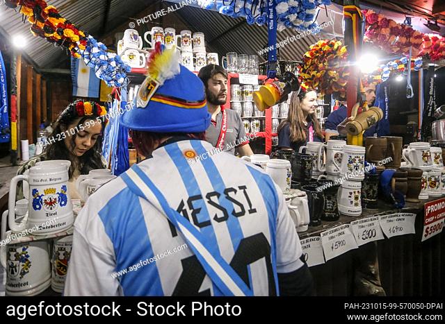 14 October 2023, Argentina, Villa General Belgrano: A man in a Messi jersey stands at a beer mug sales stand at Oktoberfest. Photo: Diego Lima/DPA