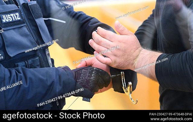 27 April 2023, Lower Saxony, Hanover: A judicial officer removes handcuffs from the defendant in the courtroom at Hanover Regional Court