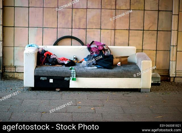 Der Schlafplatz eines Obdachlosen unter einer Brücke mit Zudecken, Müll und Essensresten