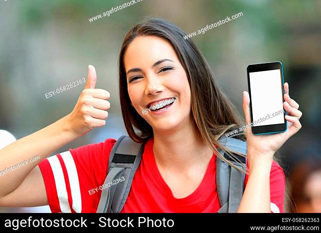 Happy teen showing a blank smart phone screen with thumbs up