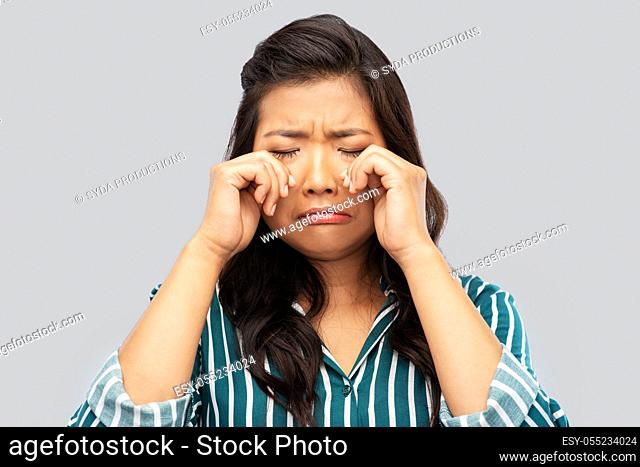 sad asian woman crying over grey background