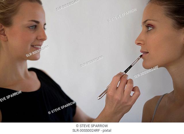 Makeup artist applying lipstick to model using lip brush