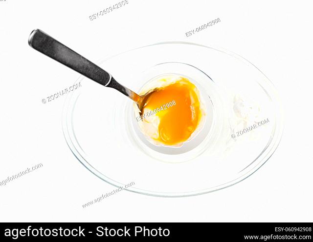 top view of open soft-boiled white egg with spoon in glass egg cup isolated on white background