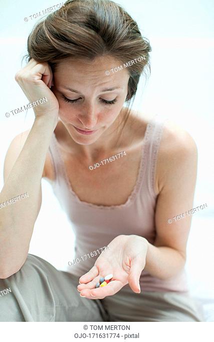 Woman holding pills and looking them