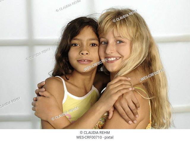 Two girls (8-11) cheek to cheek with arms around, portrait