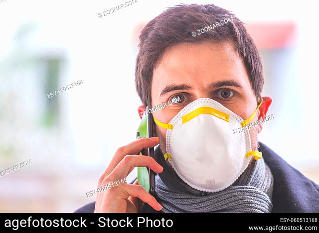 Young business man outdoors with a breathing mask and smartphone. Flue and corona season