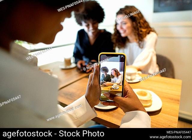 Woman photographing friends through smart phone