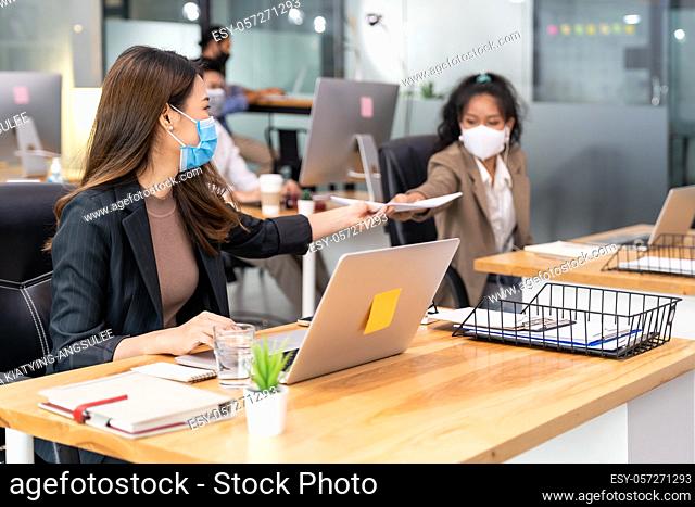 Group of interracial business worker team wear protective face mask in new normal office with social distance practice with hand sanitiser alcohol gel on table...