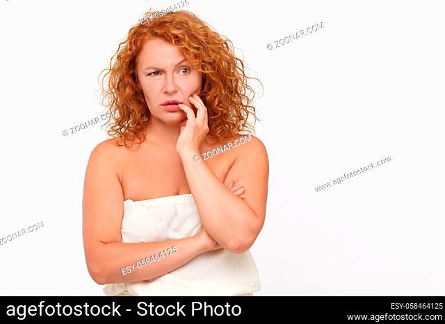 Thoughtful mature woman posing isolated on white. Beautiful red haired lady in white dress thinking about something. Expressing emotions concept