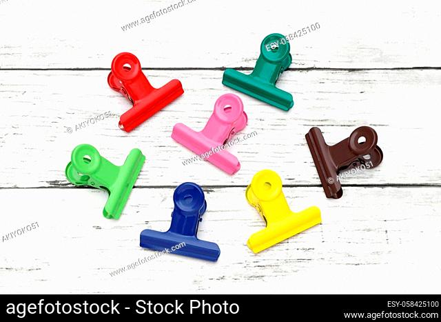 Colorful paper clips on white grunge wooden table