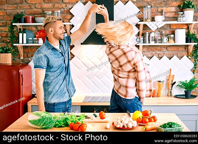 Happy young couple in love dancing in kitchen at home and having fun. Relationship, celebration, dating concept