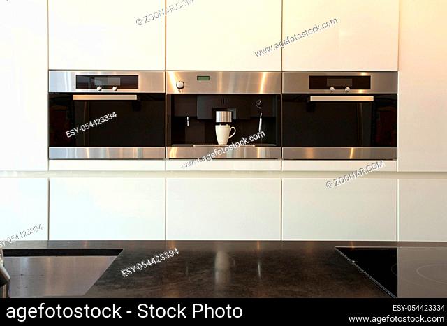 Elegant and modern white kitchen interior with oven and coffee machine close-up clean and luxury interior , induction