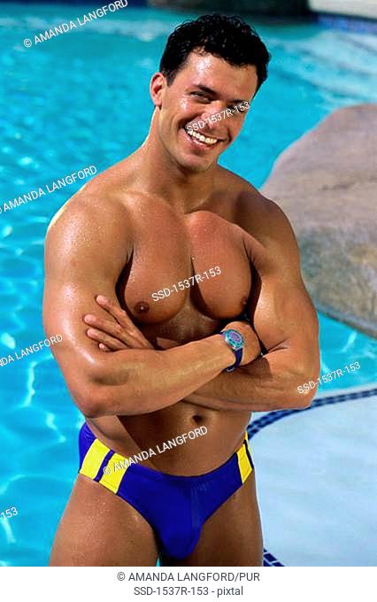 Portrait of a young man standing near a swimming pool smiling