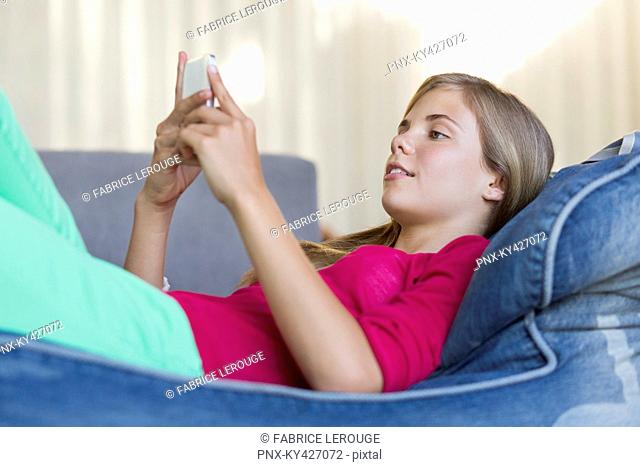 Girl lying on a bean bag and using a mobile phone