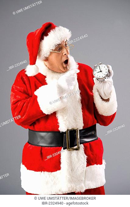 Santa Claus looking scaredly on an alarm clock