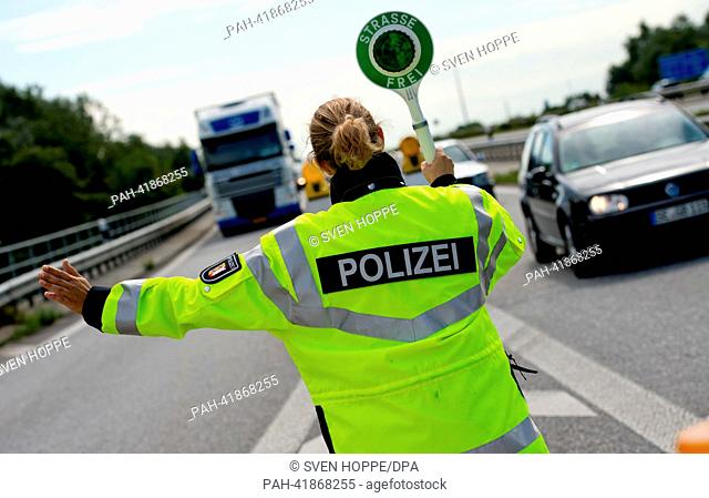 A policewoman directs a truck off the Autobahn A7 at the access to the Rade motorway bridge near Rendsburg, Germany, 19 August 2013