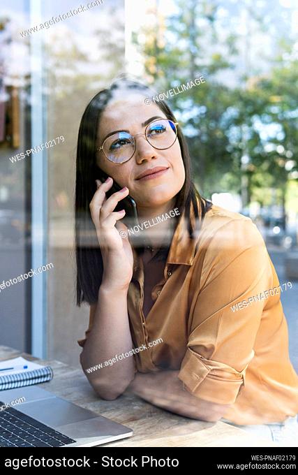 Young female professional talking on mobile phone at coffee shop