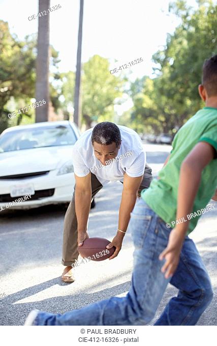 Grandfather and grandson playing football in street