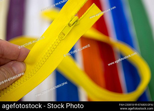 PRODUCTION - 18 August 2023, Berlin: A saleswoman holds a yellow zipper in her hand in the specialty store ""Dalink Stoffe""