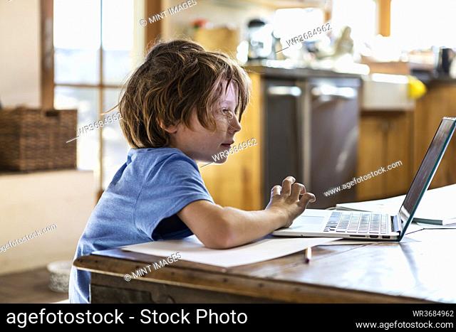 young boy using his laptop computer at home