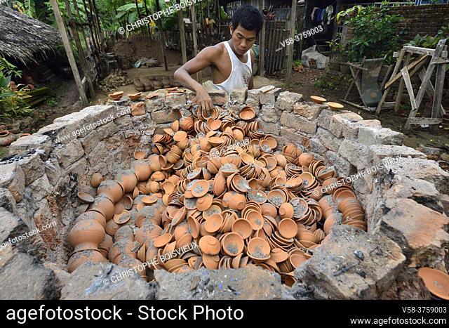 Myanmar, Mon State, Mawlamyine (Moulmein) surroundings, Mupun village, Potter picking clay cups from the oven