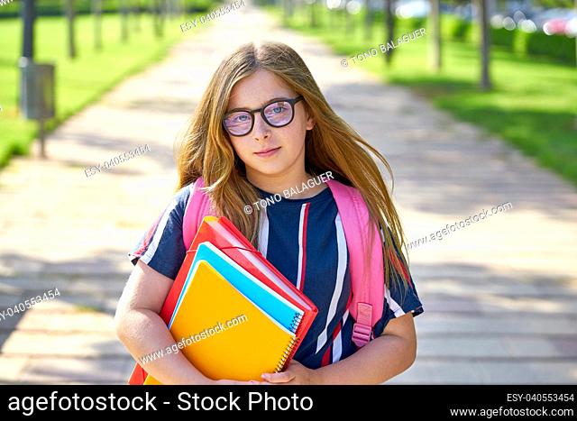 Blond kid student girl with glasses notebook and backpack in the park