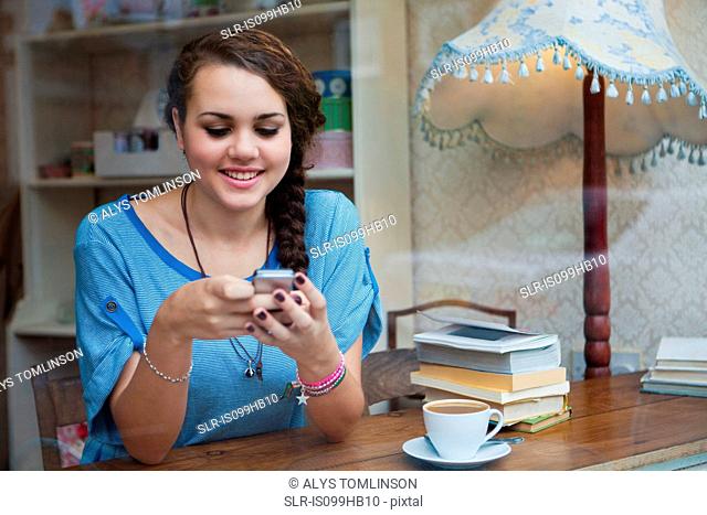 Young woman in cafe using cell phone