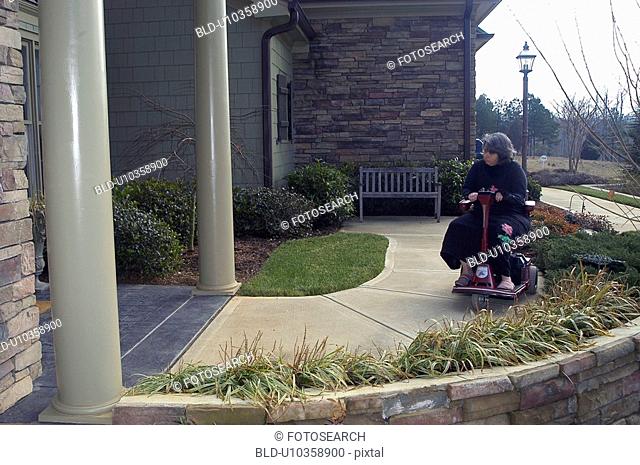 A woman using a wheelchair wheels toward the front door of a friend’s house