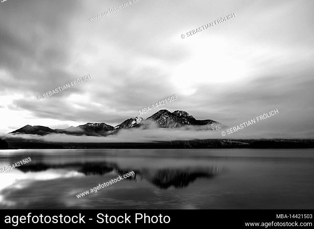 Dense clouds and fog at the Walchensee, the Herzogstand and Heimgarten are reflected in the clear water of the Alpen See