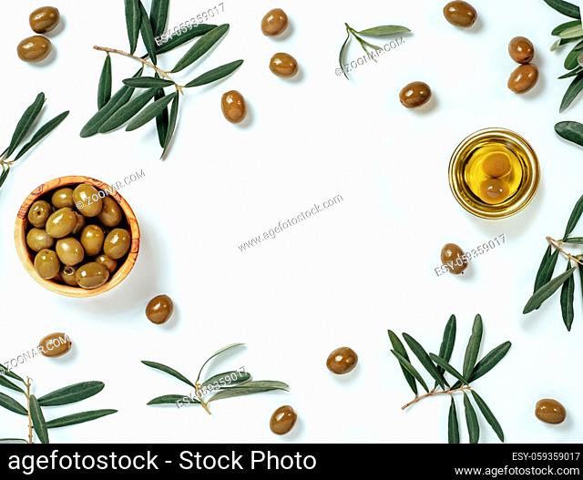 Olives and oil backgound with copy space. Set of green olives and extra virgin olive oil on white background. Top view of olives in wooden bowl and oil in glass...