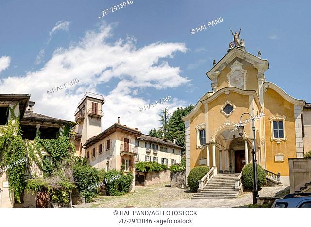 facade of old Santa Maria Assunta church and view of the buildings around it at historical touristic village, shot on bright summer day at Orta San Giulio