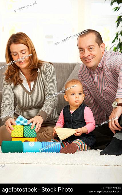 Happy family playing on floor with baby girl at home