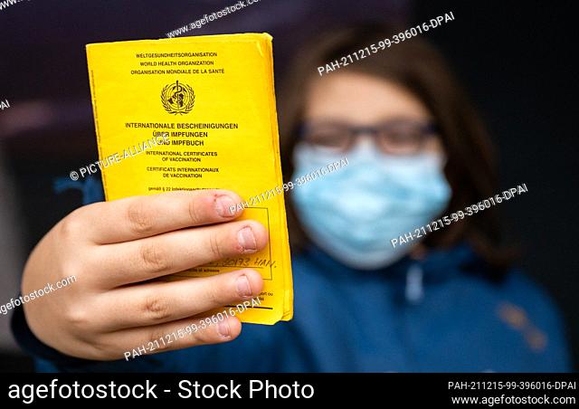 15 December 2021, Lower Saxony, Hanover: A boy shows his vaccination certificate at the vaccination centre at the zoo in the former rainforest panorama of...