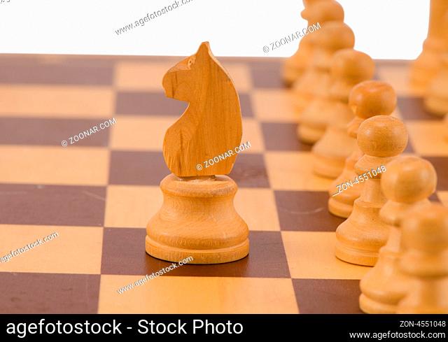 white chess figure knight stand in front of pawn line on board isolated on white