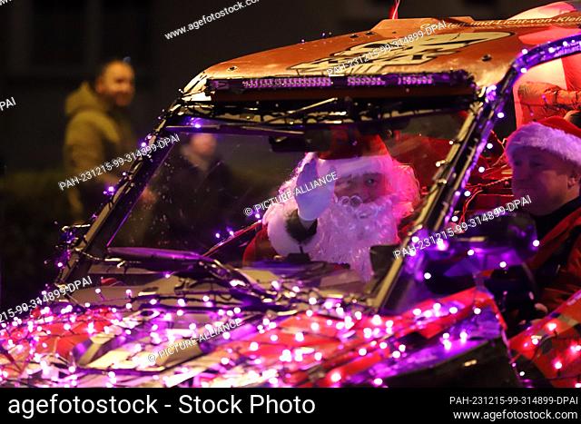 15 December 2023, North Rhine-Westphalia, Kürten: A man dressed as Santa Claus waves from an illuminated vehicle during a tractor light drive