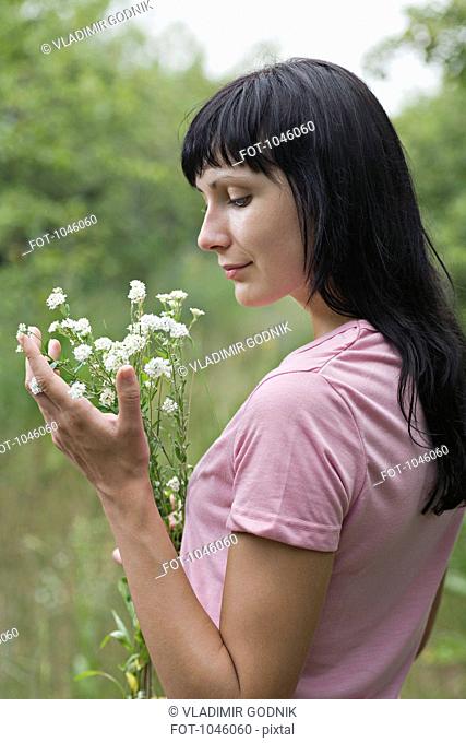 A woman admiring a bunch of wildflowers she's holding