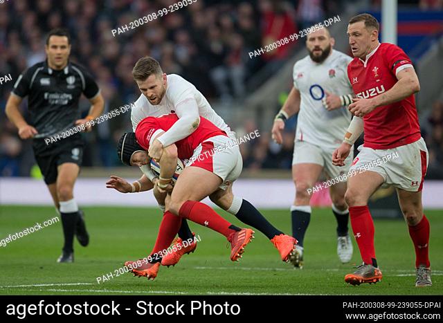 07 March 2020, Great Britain, London: Elliot Daly (England, 15) grabs Leigh Halfpenny (Wales, 15). On the right Hadleigh Parkes (Wales, 12)