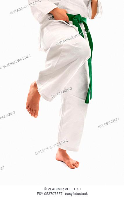 Close up shot of below the waist section of a girl in a kimono with green belt preparing for a knee kick, isolated on white background