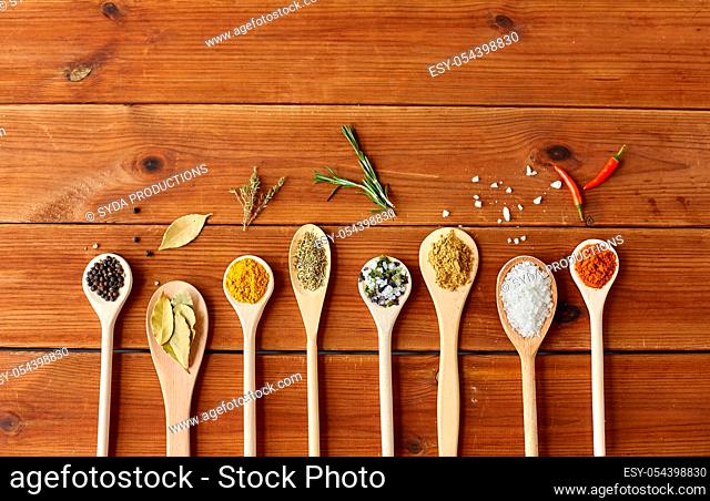 spoons with spices and salt on wooden table
