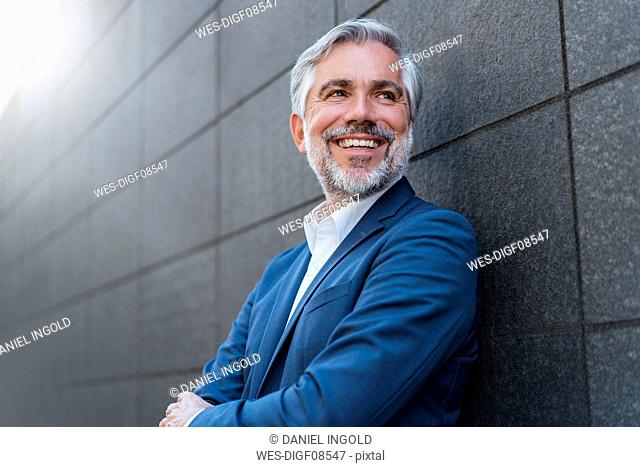 Portrait of smiling mature businessman at a wall