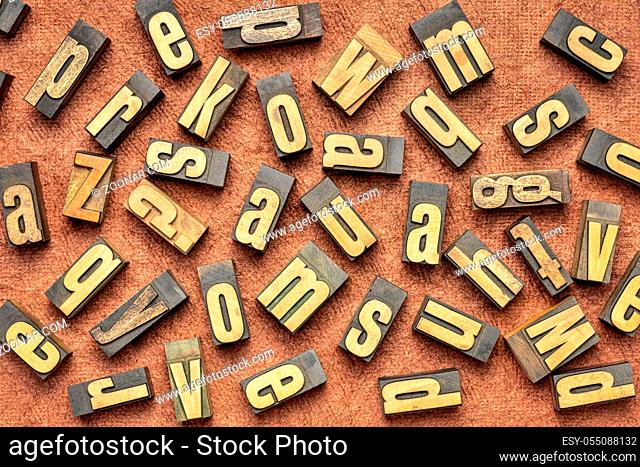 random letters overhead background - vintage letterpress wood type (inverted image) against brown handmade bark paper