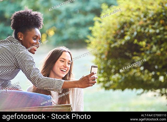 Smiling young friends talking selfie on smartphone