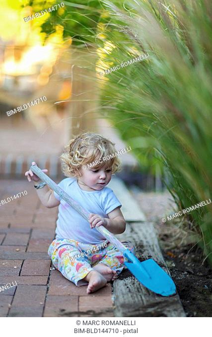 Caucasian boy playing with spade in garden
